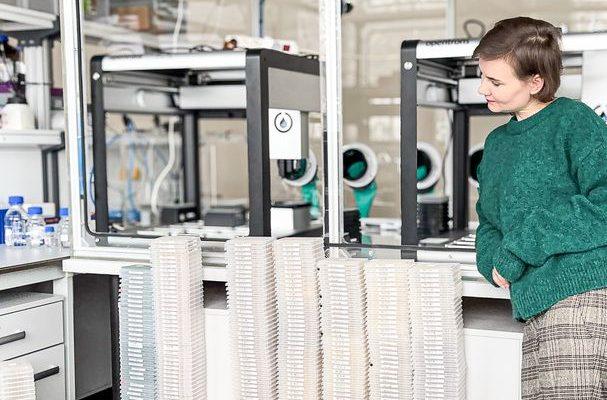 Paulina Wach, Head of Chemistry, standing next to 384-well plate stacks