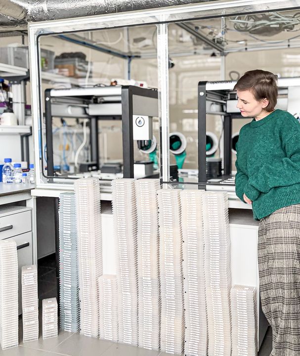 Paulina Wach, Head of Chemistry, standing next to 384-well plate stacks